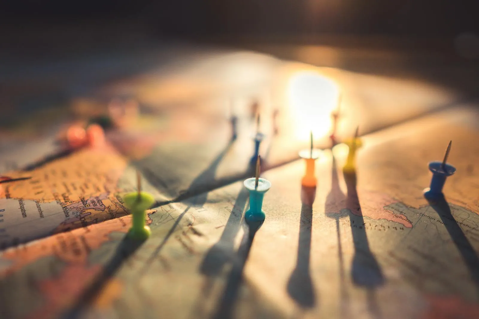 Colorful push pins marking multiple destinations on a world map at sunset — travel warnings and student insurance coverage guide 2026